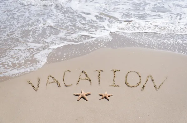 Firma "Vacaciones" en la playa de arena con estrellas de mar — Foto de Stock