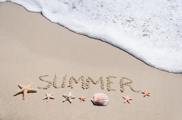 Znak "lato" na piasku z rozgwiazdy i muszla — Zdjęcie stockowe
