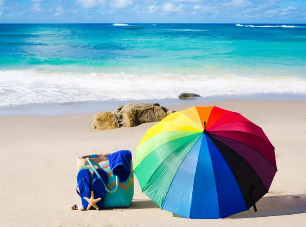 Fond d'été avec parapluie arc-en-ciel et sac de plage — Photo