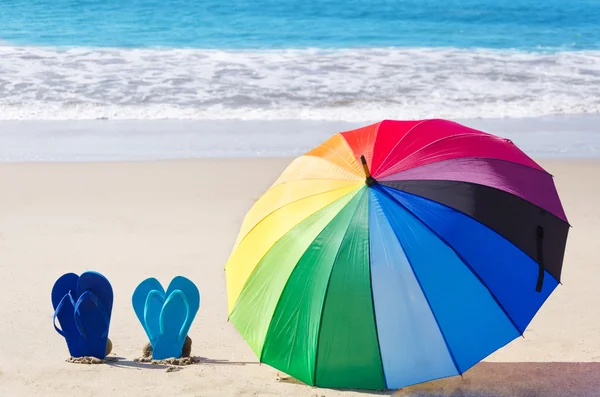 Summer background with rainbow umbrella and flip flops — Stock Photo, Image
