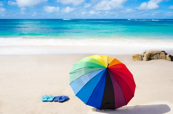 Sfondo estivo con ombrello arcobaleno e infradito — Foto Stock