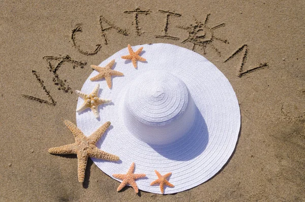 Dámský bílý klobouk na písečné pláži — Stock fotografie