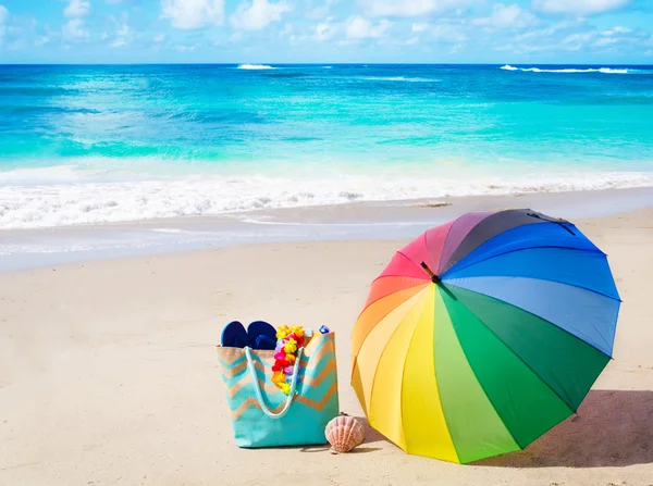 Sfondo estivo con ombrellone arcobaleno e borsa da spiaggia — Foto Stock