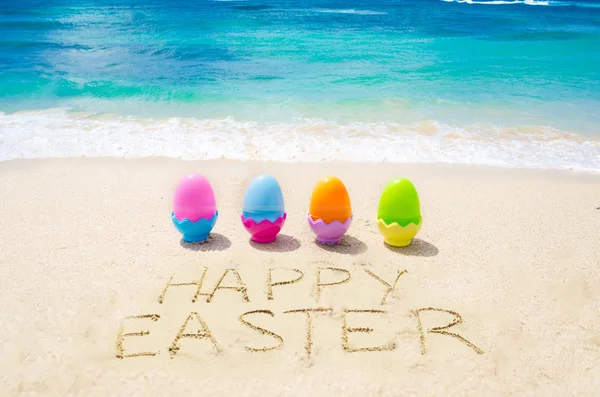 Assine "Feliz Páscoa" com ovos coloridos na praia — Fotografia de Stock