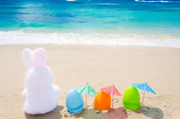 Easter bunny en kleur eieren op het strand — Stockfoto