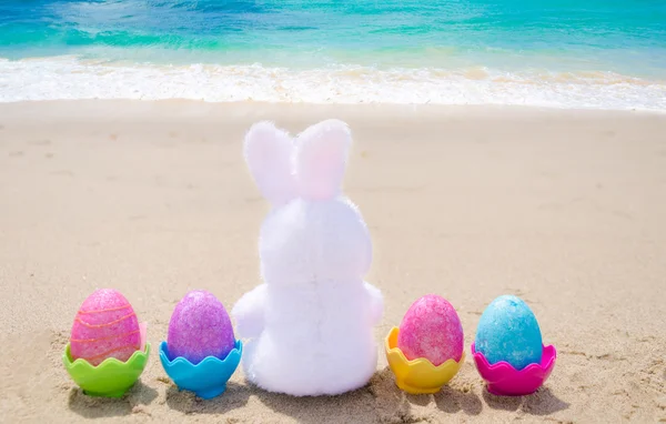 Easter bunny and color eggs on the beach — Stock Photo, Image