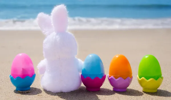 Coelho da Páscoa e ovos de cor na praia Fotografia De Stock