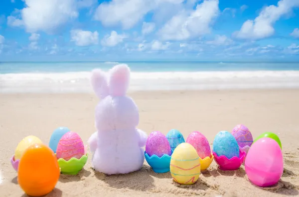 Coelho da Páscoa e ovos de cor na praia Fotografia De Stock