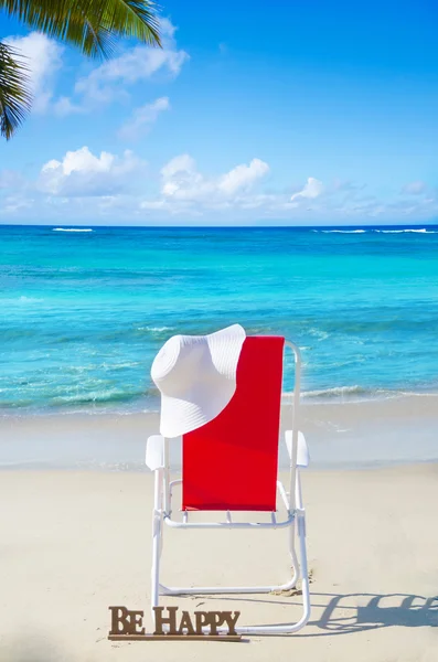 Beach chair with white hat by the ocean — Stock Photo, Image