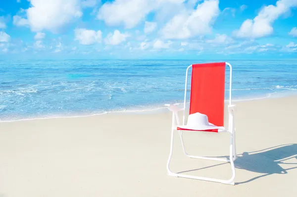 Silla de playa con sombrero blanco junto al océano — Foto de Stock