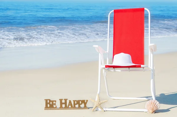 Beach chair with white hat by the ocean — Stock Photo, Image