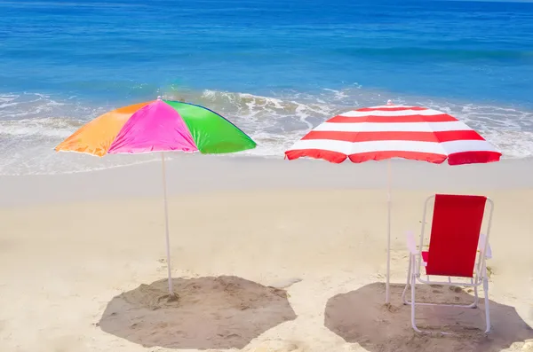 Sombrillas de playa y silla junto al océano — Foto de Stock