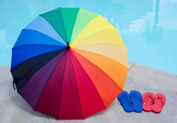 Color umbrella and flip flops by the pool — Stock Photo, Image