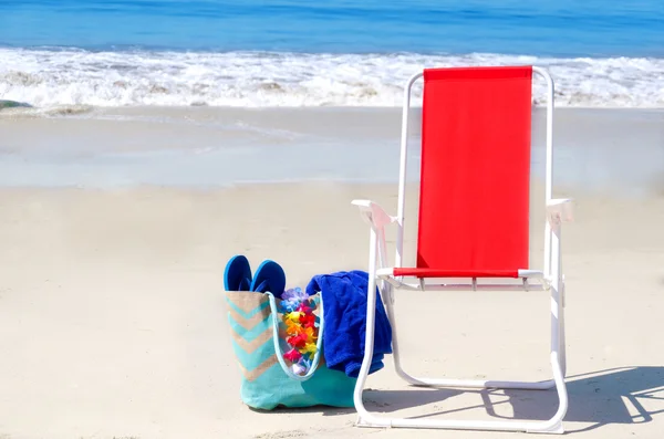 Cadeira de praia e saco com chinelos pelo oceano — Fotografia de Stock