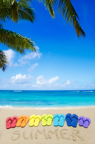 Podepsat "letní" a barevné žabky na písečné pláži — Stock fotografie
