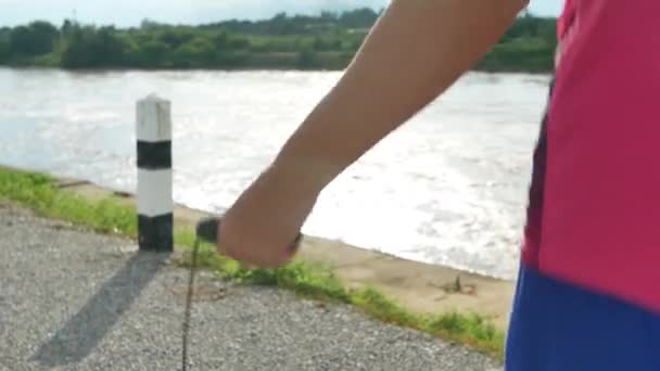 健康的少年在户外用跳绳跳跃 一位英俊的运动员在湖边的小路上用跳绳进行训练 健康的生活方式概念 手部的特写 — 图库视频影像