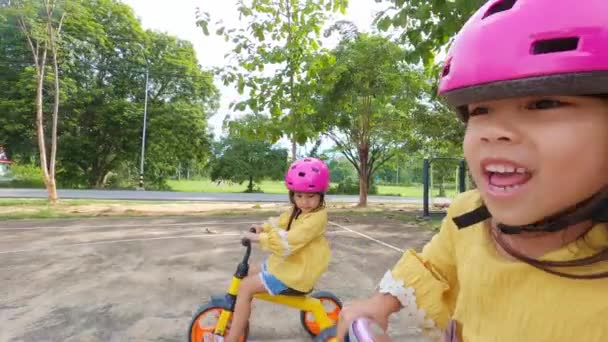 在夏天的公园里 两个戴着头盔骑自行车的小女孩 儿童户外运动 童年的快乐家人在一起的时间 — 图库视频影像