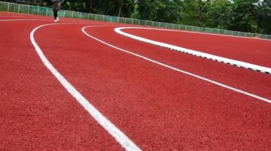 Stadyum pistinde spor kıyafetleriyle koşan atletik bir kadın. Kadın koşucu egzersiz için koşuyor. Spor Sağlıklı yaşam tarzı konsepti.