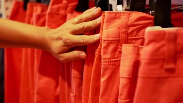 Mãos Femininas Escolhendo Tamanho Jeans Laranja Cabide Uma Loja Roupas — Vídeo de Stock