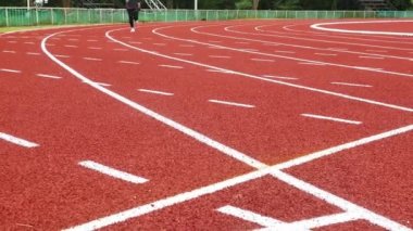 Stadyum pistinde spor kıyafetleriyle koşan atletik bir kadın. Kadın koşucu egzersiz için koşuyor. Spor Sağlıklı yaşam tarzı konsepti.