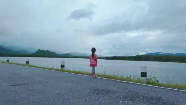 夕日の湖で美しい景色を眺めながらカメラを向ける可愛い女の子 子供の頃の幸せの概念 — ストック動画