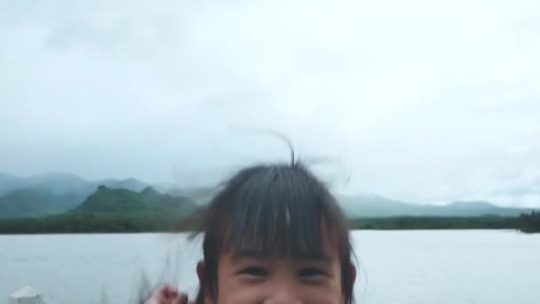 Felice Sorridente Bambina Saltando Sulla Strada Vicino Lago Guardando Fotocamera — Video Stock