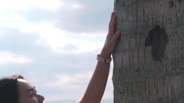 Kadın turist parkta bir ağaç gövdesine dokunuyor. İnsan doğayı ve çevreyi önemsiyor..