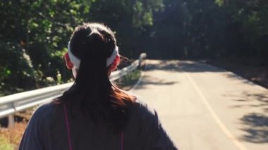 Atletik kadın asfalt yolda koşuyor sonbaharda ormanda koşuyor. Gün batımında doğada koşan kadın koşucu. Spor Sağlıklı yaşam tarzı konsepti.