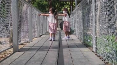 İki güzel kız kardeş hayvanat bahçesindeki geyiği beslemek için çitli ahşap bir geçitte yürüyorlar. Tatilde ailesiyle harika vakit geçiriyor..