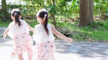 Aktif küçük kız kardeşler parkın bahçesinde koşuyorlar. Çocuk parkında gülümseyen ve gülen mutlu kız çocukları. Oyun kavramı çocuklukta öğrenmektir..