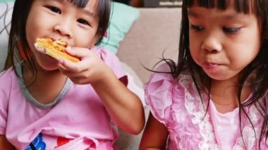 Pizza yiyen tatlı kız kardeşler. Evde pizza partisinde pizzadan bir ısırık alan aç çocuklar. Aile tatili kavramı.