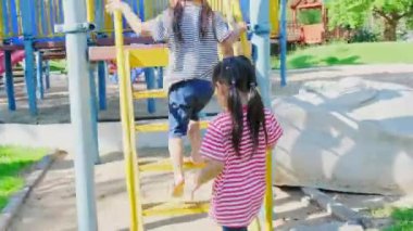 Aktif küçük kız kardeşler parkın bahçesinde koşuyorlar. Çocuk parkında gülümseyen ve gülen mutlu kız çocukları. Oyun kavramı çocuklukta öğrenmektir..