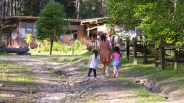 Anne ve iki kız el ele tutuşup bir bahar günü parkta yürüyüş yapıyorlar..