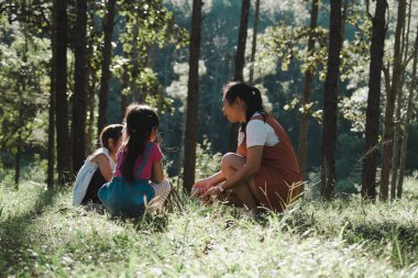 Mother and two daughters collecting firewood and kindling bonfire at camping place in forest. Family and children making campfire on nature woods. Family camping, spending time together on vacation. clipart