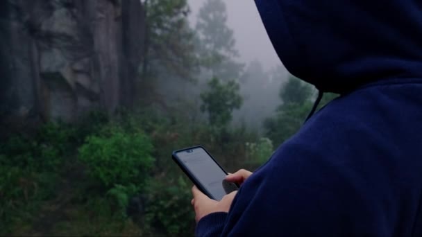 하늘색 후드를 스마트폰을 사용하여 소매를 여행자는 안개가 경치를 즐긴다 — 비디오