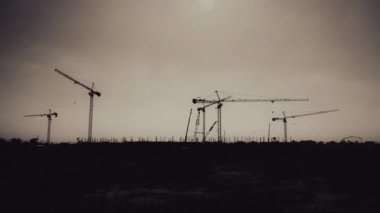 Gün batımında kule vinci silueti ve büyük binaların inşaat alanı. Gün batımında arka planda vinçleri olan yeni inşaat alanı.