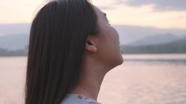 Gölün kenarında duran genç bayan turist gün batımında doğanın güzel manzarasının tadını çıkarıyor. Yaşam tarzı ve açık hava turizm kavramları.
