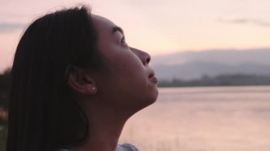 Gölün kenarında duran genç bayan turist gün batımında doğanın güzel manzarasının tadını çıkarıyor. Yaşam tarzı ve açık hava turizm kavramları.