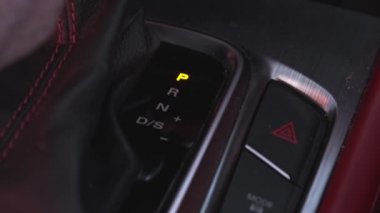Close-up of a driver holding an automatic gear lever to change gears in a car. Automatic transmission, automatic gear shift, is moved from D Drive to P Park.