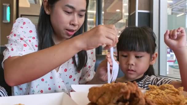 かわいいアジアの女の子が一緒にファーストフードレストランでフライドチキンとフライドポテトを食べています — ストック動画