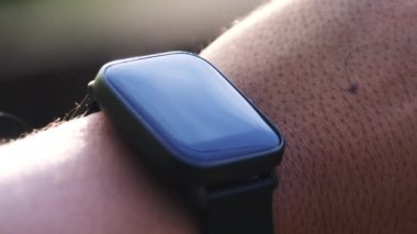 Asyalı bir erkek sporcunun bileğindeki akıllı bir ayak izinin yakın çekimi..