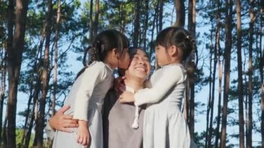İki tatlı kardeş kız parkta genç ve güzel bir anneyle eğleniyor. Annelik ve aile kavramı. Çocuklar tatilde aileleriyle vakit geçirirler..