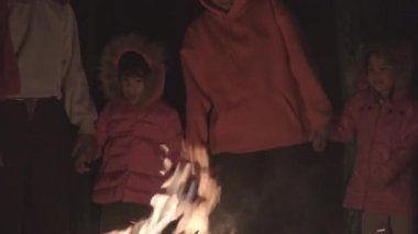 Aile, ormanda kamp ateşinin yanında ısınır ve sohbet eder. Çam ormanında kamp ateşinin yanında. Turizm ve kamp kavramları.