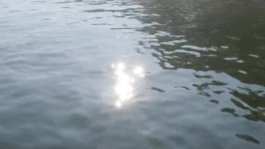 Gün doğumunda güneş ışığını kapat. Kış sabahı küçük dalgalarla göle yansıyan yansıma..