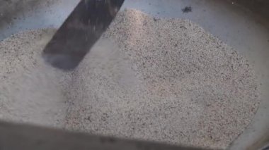 Asyalı köylüler köy dükkanlarında satılmak üzere tavada susam kızartıyorlar..