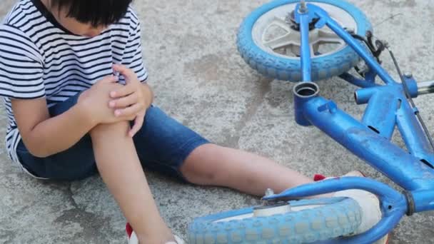 夏の公園で自転車から落ちた後 地面に座っている悲しい少女 自転車に乗っている間に子供がけがをした — ストック動画