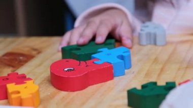 Evde pijama giyen, tahta yapboz oynayan tatlı bir genç kız. Çocuklar için eğlenceli eğitim aktiviteleri.