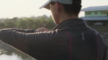 Sağlıklı genç çocuklar akıllı saat kalp atış hızı monitörüne bakıyor. Genç bir erkek sporcu dışarıda koşuyor ve akıllı bir saat üzerinden ilerlemesini kontrol ediyor. Sağlıklı yaşam tarzı kavramı.