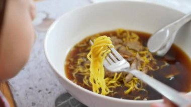 Restoranda Tayland eriştesi yiyen tatlı küçük bir kız. Mutlu ve sağlıklı çocukluk kavramı. Yemeği odakla.
