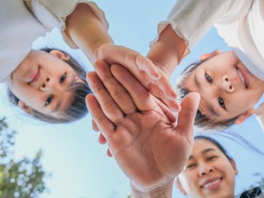 Sıcak ve güneşli bir günde aile fertlerinin elleri mavi gökyüzü arkaplanına karşı birleşir. Mutlu insanlar ya da takım katılımı.